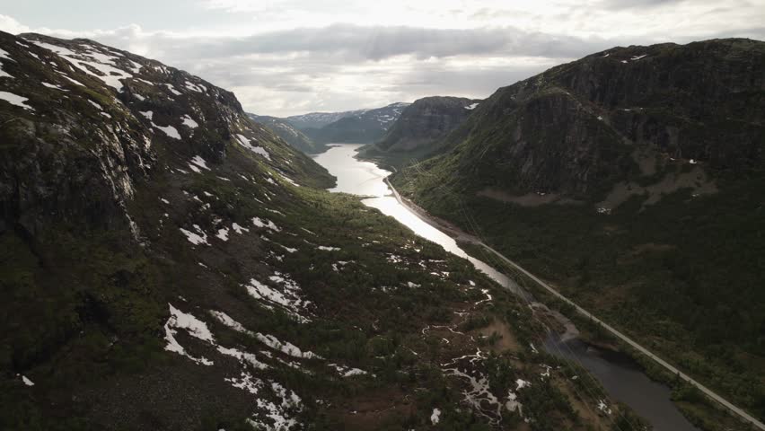Aerial view of a long lake running between two mountains with some snow on the peaks, Dalen, Telemark, Norway.