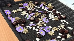 Rotating close-up of a decorative black basket filled with chestnuts, white pebbles, purple flowers and wooden snowflake ornaments. The camera moves slowly around the arrangement. - Powered by Shutterstock - Get 15% off with code: PIKWIZARD15