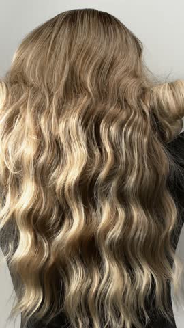 Blonde wavy hair moving in slow motion. Texture of female hair close-up.
