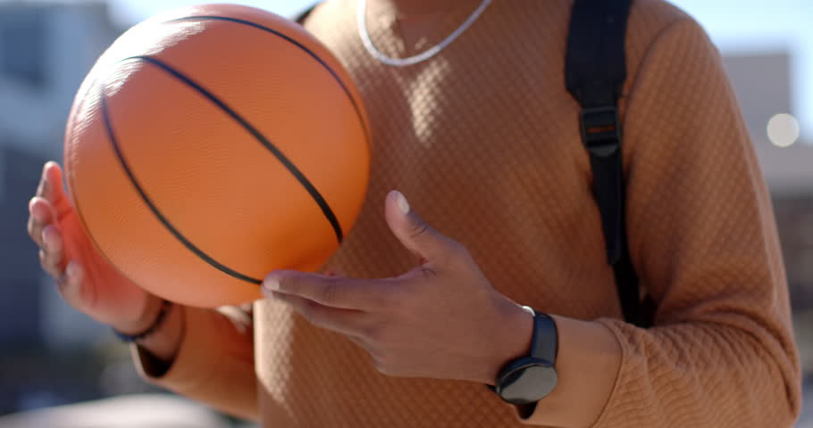 Panning shot revealing African American male carrying basketball on rooftop preparing for practice. Urban, athletic, casual, vibrant, energetic, contemporary, active