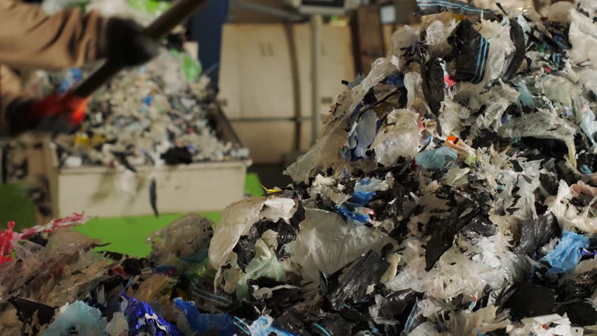 Shredded plastic waste moving on a conveyor belt in a recycling factory for sorting and processing