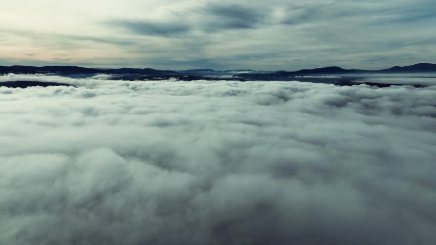 Aerial drone view above the clouds with forest hills, rivers, and houses in Washington State USA