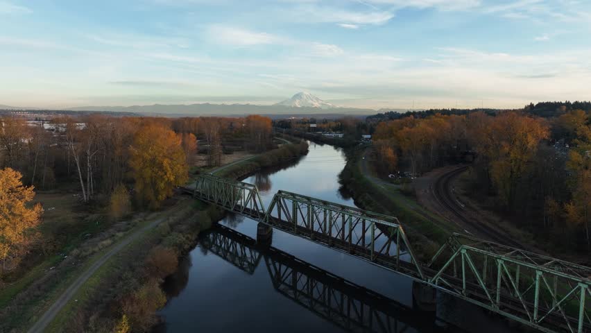 Aerial drone view of river, steel bridge, and Mount Rainier volcano in Washington State USA at sunset