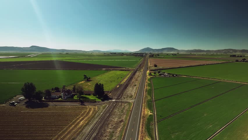 Aerial drone view of farmland, fields, house, and road with mountains in Oregon, USA