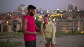 Multiracial athletic couple taking a break after running in the city at dusk. Young exhausted woman is catching her breath while the man is checking their performance on his fitness tracker - Powered by Shutterstock - Get 15% off with code: PIKWIZARD15