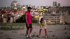 Professional personal trainer motivating a tired female runner who is catching her breath after an intense workout with a beautiful city skyline at dusk in the background - Powered by Shutterstock - Get 15% off with code: PIKWIZARD15
