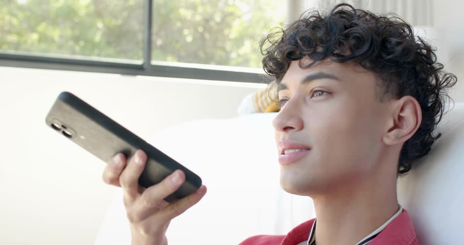 Man on couch raising phone speaking, activating HUD lines, nodes peaking then fading for tech demo. Person, device, promo, modern, electronics, livingroom, foliage