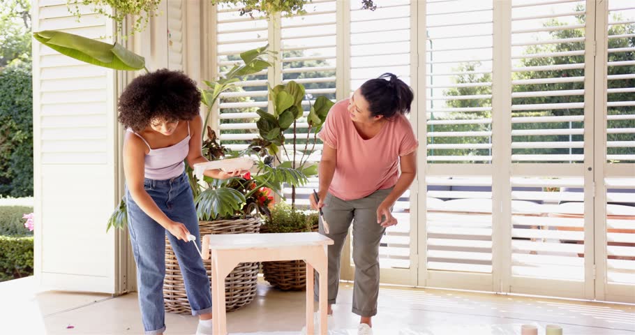Mom and daughter pointing, rolling paint table for DIY as pink blue swirls partially obscuring them. Teamwork, sunroom, daylight, homeimprovement, decor, furniture, plants