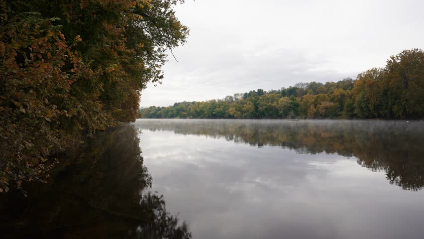 Morning mist drifting over the Upper James River at James River State Park, with early autumn colors reflected in the still water.