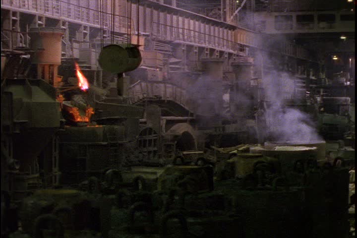 Steel works in Verkh-Isetsky, Russia. Static WS showing huge pieces of iron machinery. A smoking vat is in the background, flames from furnace are visible on the left.