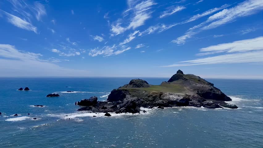 A drone view flying directly over Castle Rock off the coast of Crescent City, California, capturing rugged cliffs, seabirds, and the wild Pacific shoreline