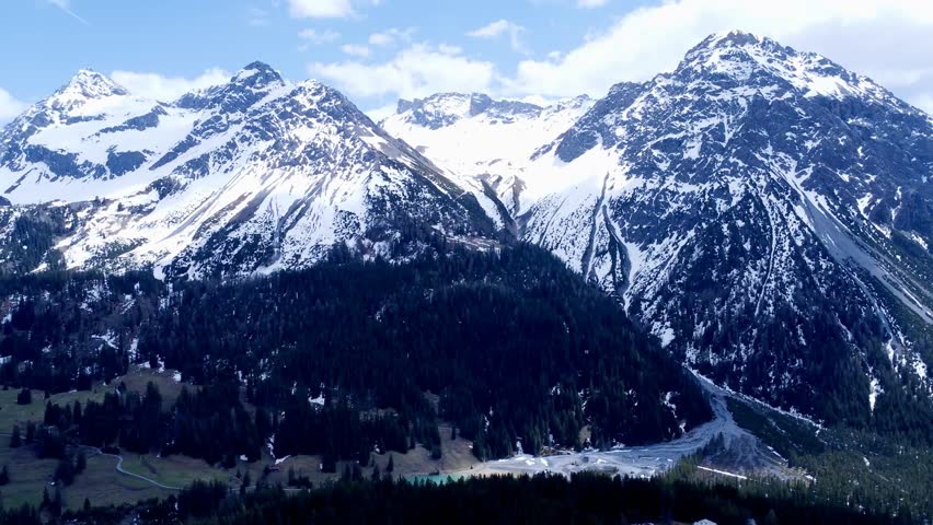 A 360° aerial panorama showcasing the snow-capped mountains encircling Arosa, Switzerland, revealing a breathtaking alpine winter landscape.