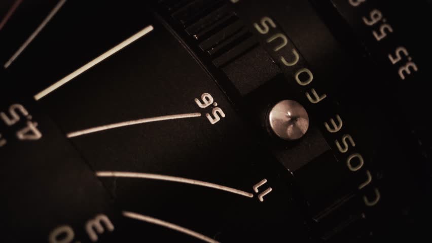 Camera lens aperture and focus ring adjusting the photoshoot. A macro video shot, showing the details of a vintage manual lens with number meters and text