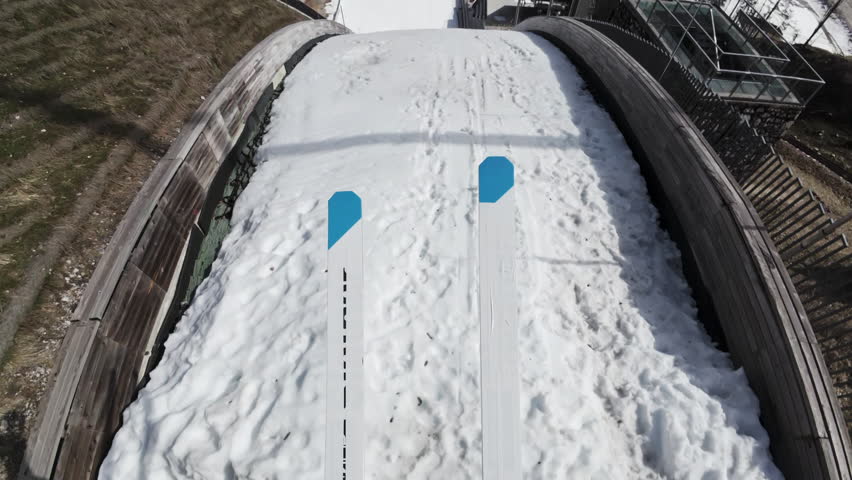 Ski jumper on the skis sliding down a jumping ramp, achieving an explosive jump, flying and landing gently and safely on snow, point of view shot.