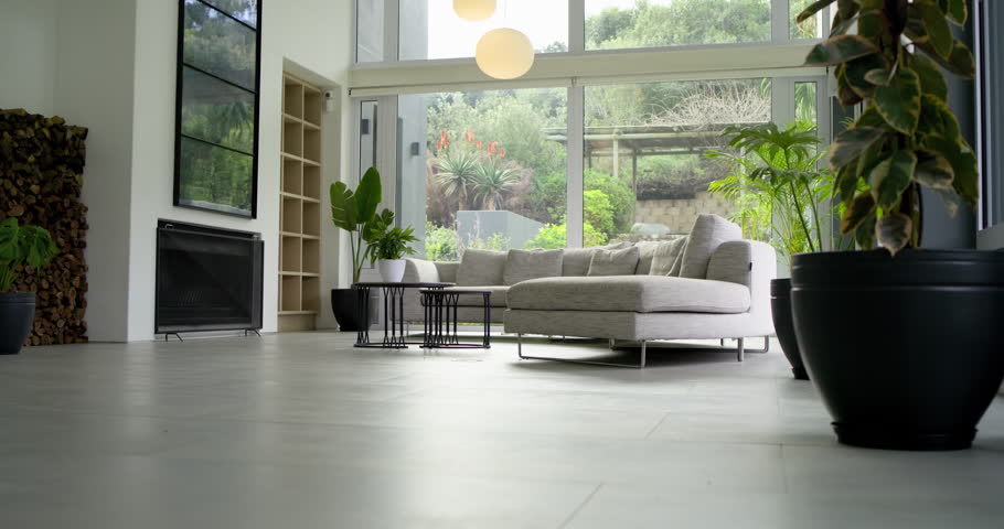 Camera starting low in living room, tilting upward showing sectional sofa, tables, pendants, garden. Interior, contemporary, minimalist, tranquility, elegance, decor, architecture