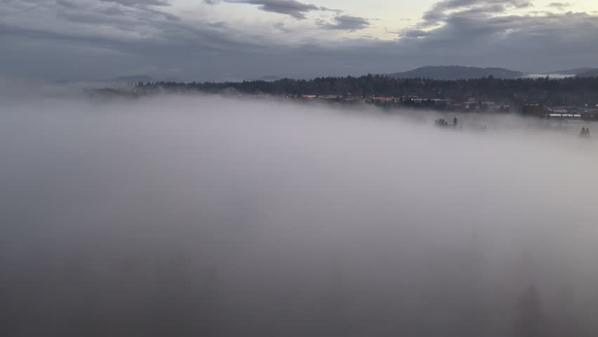 Morning fog drifts through a scenic, forested Pacific Northwest landscape near Portland, Oregon. Fog and mist forms when moist air cools to its dew point, causing water vapor to condense.