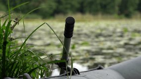 A close view of an inflatable boat paddle resting near lush lakeside vegetation in Poland, with gentle summer breeze and insects moving over the calm, lily-covered water. - Powered by Shutterstock - Get 15% off with code: PIKWIZARD15