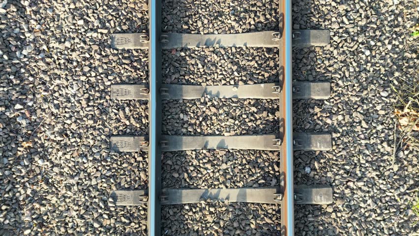 Close-up view of railway tracks showcasing metal rails and gravel, with a gradual zoom in capturing the intricate details of the scene, emphasizing texture and structure