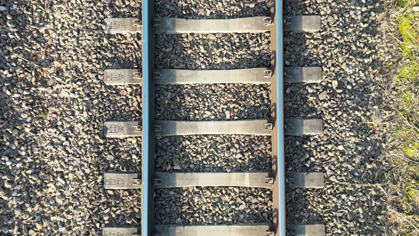 Close-up view of railway tracks showcasing metal rails and gravel, with a gradual zoom in capturing the intricate details of the scene, emphasizing texture and structure