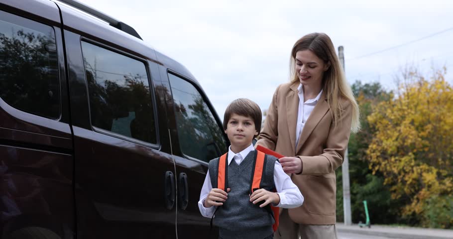 Mother taking her son to school near car outdoors