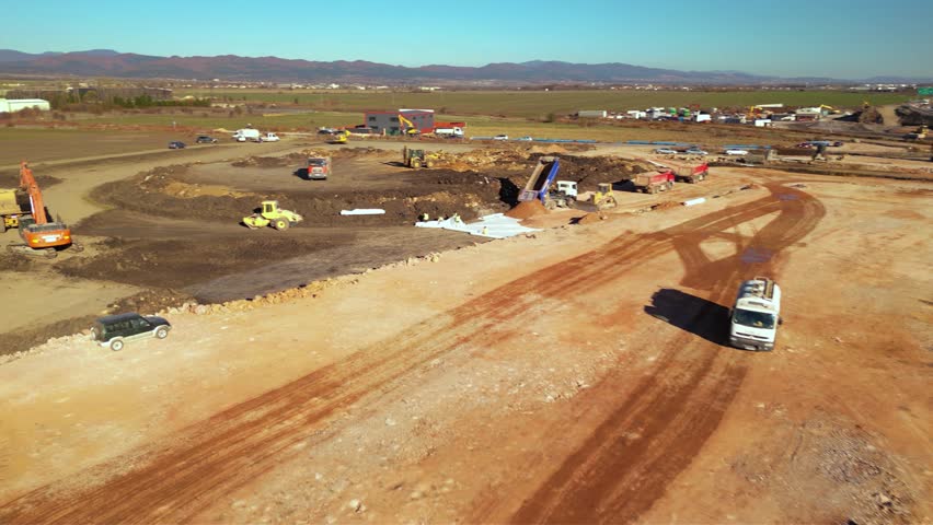 Top-down aerial view of a construction crew in safety gear installing geotextile fabric across a graded earth surface with a bulldozer pushing aggregate, capturing the scale of sitework, material hand - Powered by Shutterstock - Get 15% off with code: PIKWIZARD15