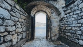 stone archway overlooking sea through doorway, framed by weathered masonry and rugged walls, ancient coastal passage opens onto calm harbor beyond, pebble floor and mossy - Powered by Shutterstock - Get 15% off with code: PIKWIZARD15