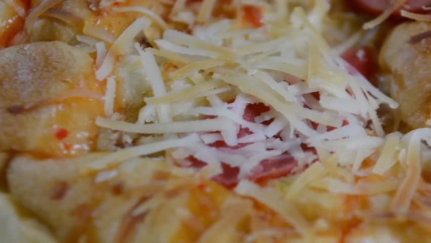 Close-up of Savory Pizza Bread or Spicy Cheese and Sausage Bun Topped with Shredded Cheese, Sauce, and Scallions on a Black Background