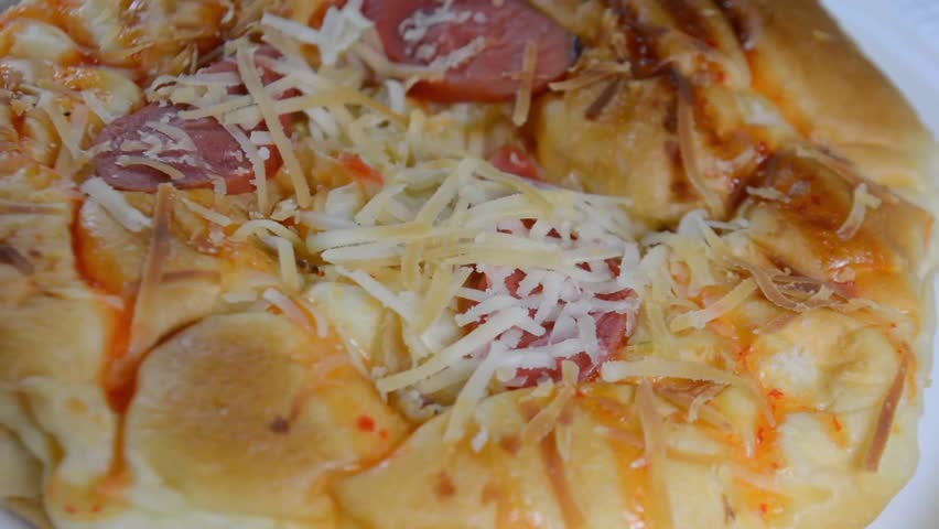 Close-up of Savory Pizza Bread or Spicy Cheese and Sausage Bun Topped with Shredded Cheese, Sauce, and Scallions on a Black Background
