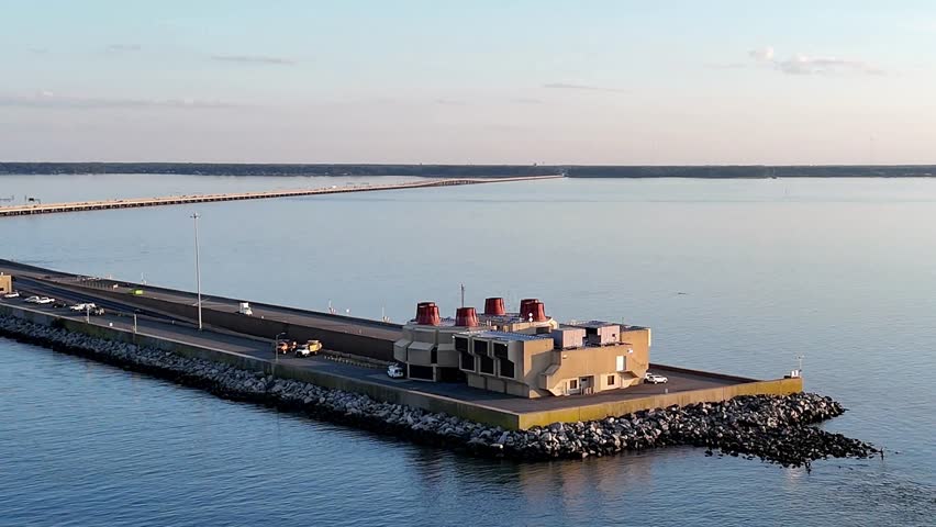 An expansive aerial shot of a Merrimac Memorial Bridge Tunnel crossing tranquil blue water, with a distant Newport News Harbor, open sky, conveying travel, infrastructure, and modern coastal scenery.