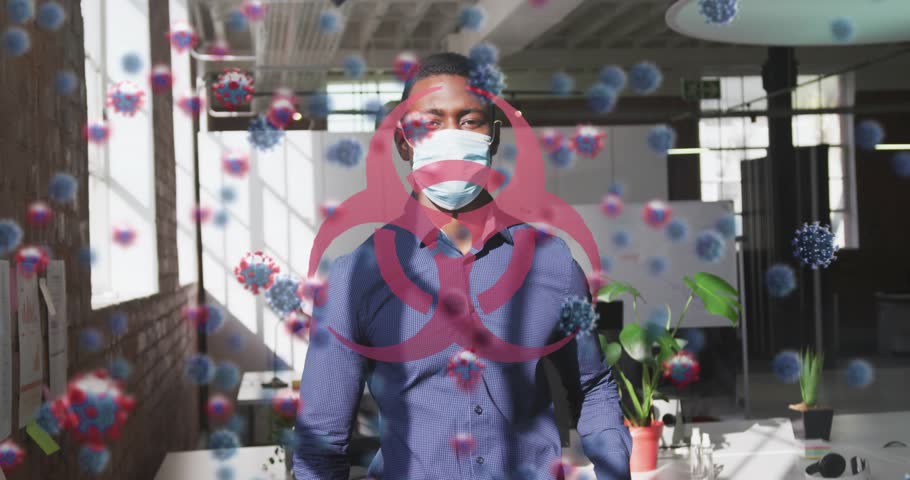 Man raising hand and lowering mask, revealing smile with biohazard virus overlay obscuring scene. Office, loft, daylight, professional, headset, monitor, plants