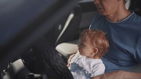 dad plays with his son in car. people family and children concept. beautiful little kid sit and plays on his father's lap and turn the lifestyle steering wheel of his car - Powered by Shutterstock - Get 15% off with code: PIKWIZARD15
