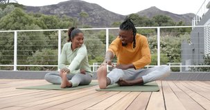 Seated on yoga mats Diverse friends shifting into hamstring stretch on wooden deck warming muscles. Fitness, outdoor, wellness, stretching, collaboration, landscape, health - Powered by Shutterstock - Get 15% off with code: PIKWIZARD15