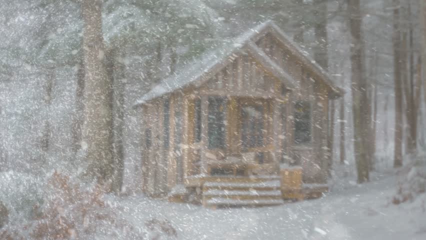 Rustic wooden cabin stands in a serene snowy forest, a beautiful winter landscape photography scene with falling snow.