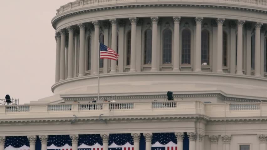 United States flag waving in front of the Capitol Dome rotunda, capturing patriotism, iconic landmarks, and American political architecture.