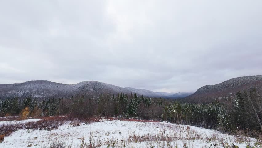Aerial winter rush through a narrow valley where river reflections create shimmering highlights along deep snowy slopes.