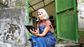 Experienced senior female florist sitting on her greenhouse doorstep while checking orders online and managing her small business with a modern tablet, embracing new technology - Powered by Shutterstock - Get 15% off with code: PIKWIZARD15