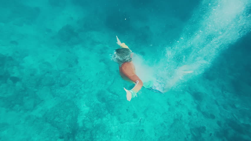 Teen boy swims underwater with bubbles