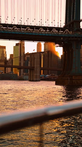 Sunbeam between New York bridges. Golden light breaks between the East River bridges and glows across Manhattan towers.