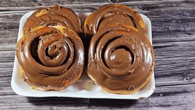 Chocolate cinnamon rolls, a type of sweet roll or pastry that made of rolled dough with a cinnamon and sugar mixture then topped with chocolate glaze or frosting, popular in North Europe and America - Powered by Shutterstock - Get 15% off with code: PIKWIZARD15