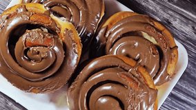Chocolate cinnamon rolls, a type of sweet roll or pastry that made of rolled dough with a cinnamon and sugar mixture then topped with chocolate glaze or frosting, popular in North Europe and America - Powered by Shutterstock - Get 15% off with code: PIKWIZARD15