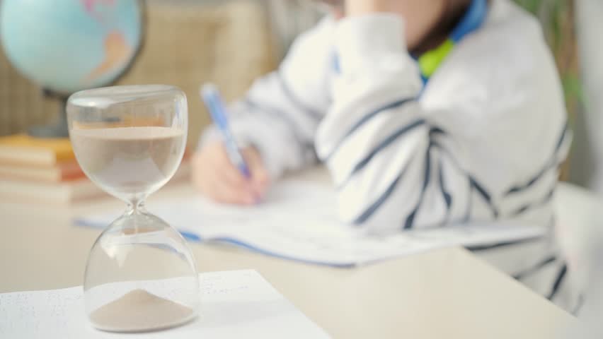 Teenager Student studying doing homework at desk with hourglass, education, knowledge and time management, writing, learning process, exam prep, child training, concentration and discipline sand timer - Powered by Shutterstock - Get 15% off with code: PIKWIZARD15