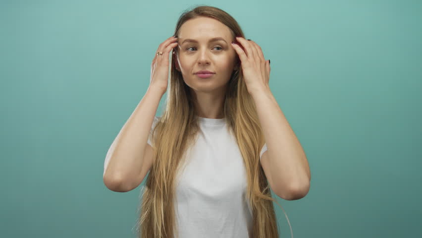 Woman proudly standing with long hair against an isolated green background, exuding confidence and positivity, epitomizing self-assuredness and beauty in a serene setting.