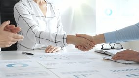 Business partners shaking hands in office with financial charts, laptop and reports on table, symbolizing success, teamwork, agreement, collaboration and corporate growth. Businesspeople handshake - Powered by Shutterstock - Get 15% off with code: PIKWIZARD15