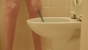 woman scrubbing toilet bowl with brush in tiled bathroom, focused hygiene routine, short sleeves and shorts, rinse - Powered by Shutterstock - Get 15% off with code: PIKWIZARD15