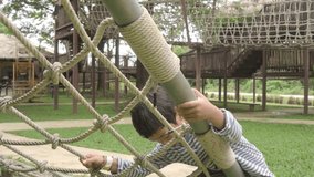 Asian boy climbing rope net on playground, learning and exploring outdoor activity - Powered by Shutterstock - Get 15% off with code: PIKWIZARD15