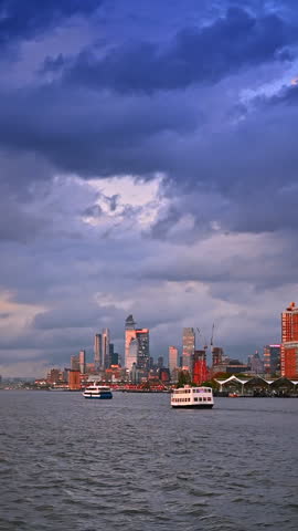 Dramatic cloudscape covering the sky over the Hudson River in New York, USA. Riverboats move by the riverscape at dusk time. Vertical video.