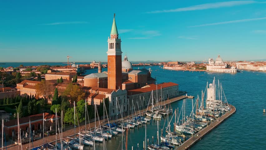 Aerial view of San Giorgio Maggiore island and Grand Canal in Venice, Italy, at sunrise. Stunning landscape of the Venetian lagoon with historic architecture and calm morning atmosphere.
