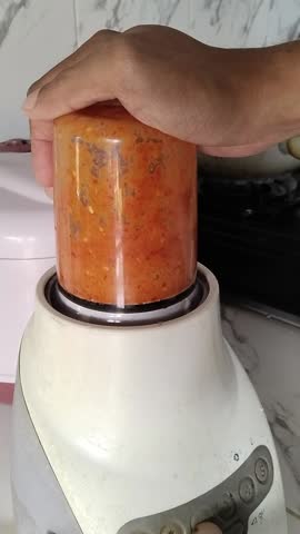 Traditional Indonesian sambal ingredients, red chilies, curly chilies, garlic, shallots, and shrimp paste, processed in a blender. Great for recipes, food ingredients, and spice preparation visuals