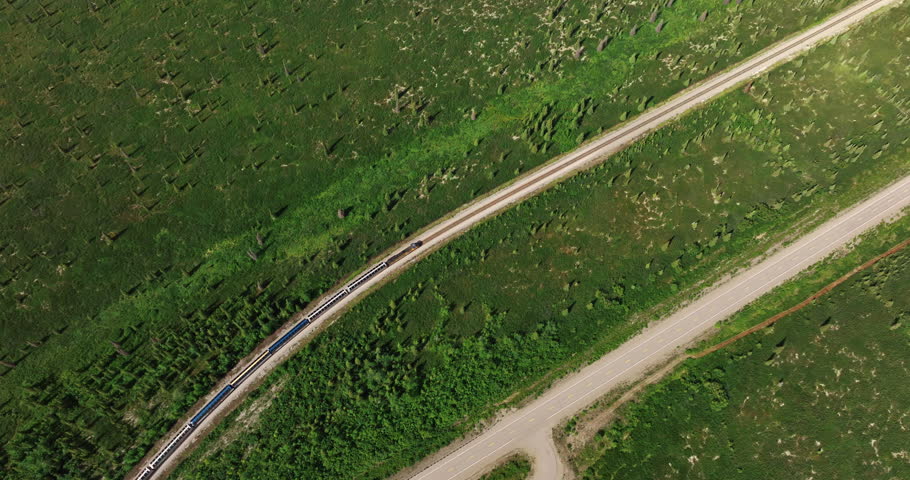 Fast train moving quickly by the railways in the valley. Top view on the transport in Alaska.
