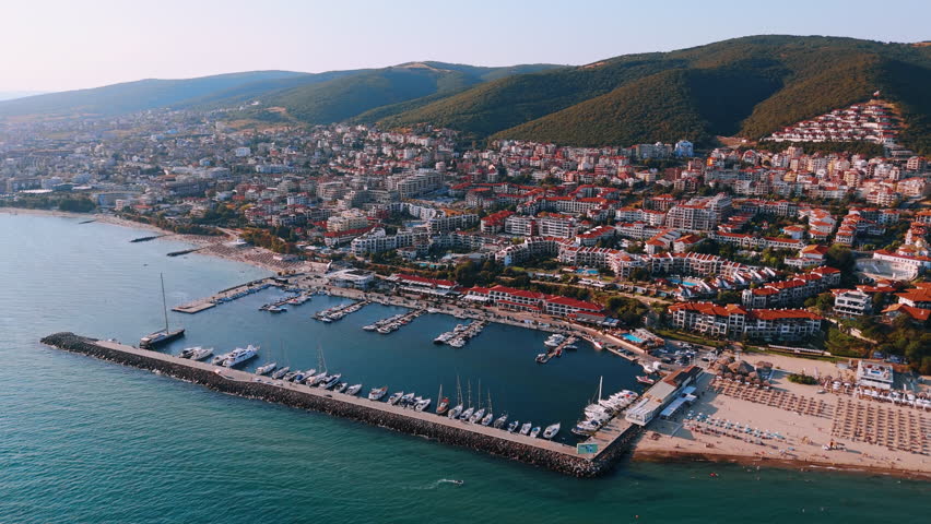 Beautiful resort city scattered on the slopes of the mountains at the Black Sea coast. Drone footage near the yacht club and sandy beach of Sveti Vlas, Bulgaria.